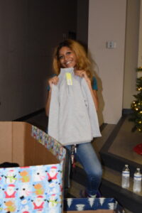 Marissa holds up a sweatshirt she's considering for her child at our 2022 Holiday House. 